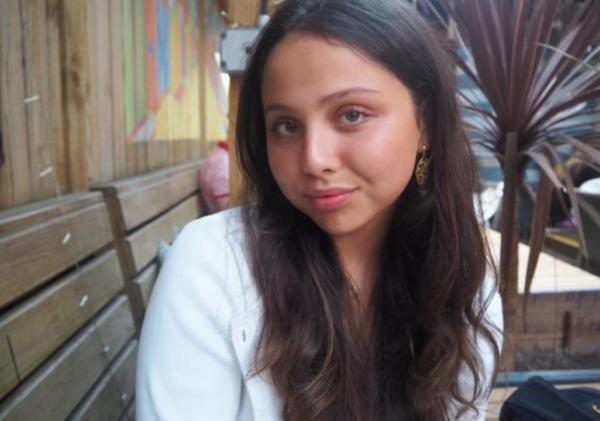 Agapov in a white top looking at the camera and smiling