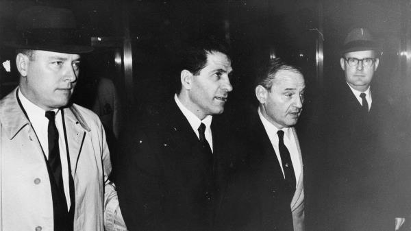 So<em></em>nny Franzese standing in between two men in suits looking serious.