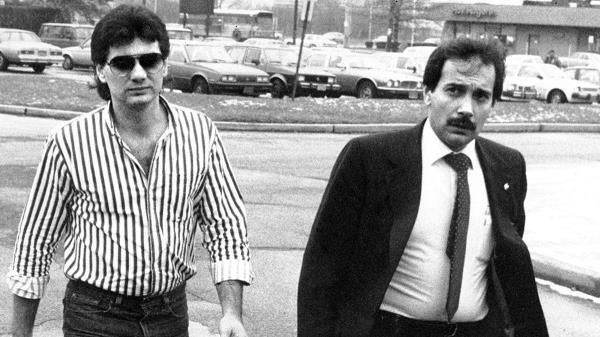 Michael Franzese in a striped shirt and glasses walking into court next to a man in a suit.