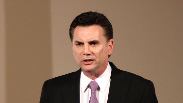 Michael Franzese wearing a suit and holding a mic.