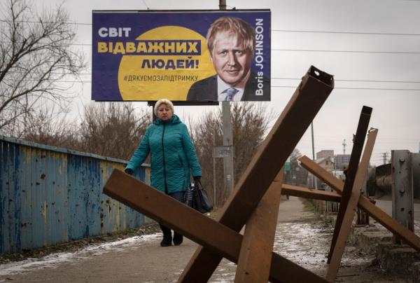 Woman walks in front of a sign in Ukraine that thanks Boris Johnson for his support.