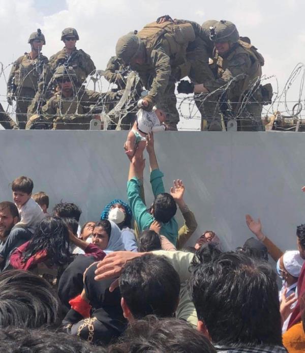 An US Marine gabbing an infant over a fence during the evacuation.