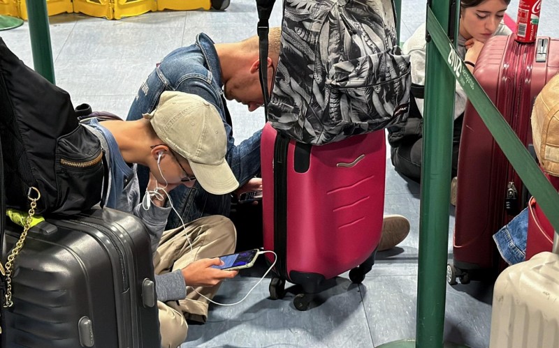 Passengers use their pho<em></em>nes as they wait at Lisbon Airport amid a global IT outage