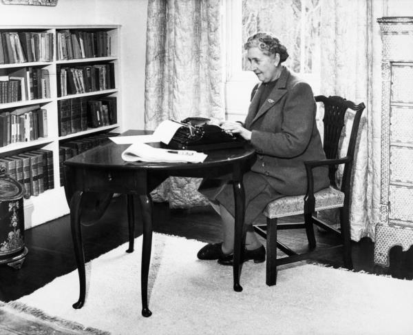 Agatha Christie at a table with a typewriter