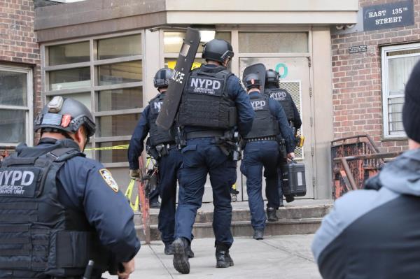 Police enter the apartment building after the shooting.