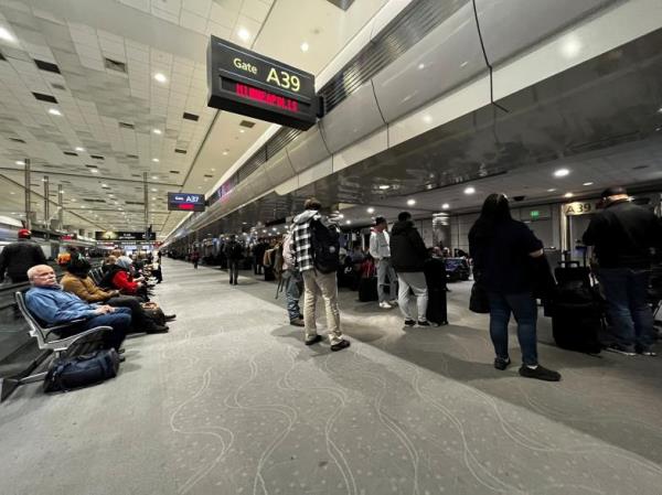People wait at the Denver Internatio<em></em>nal Airport, as flights were grounded after FAA system outage.