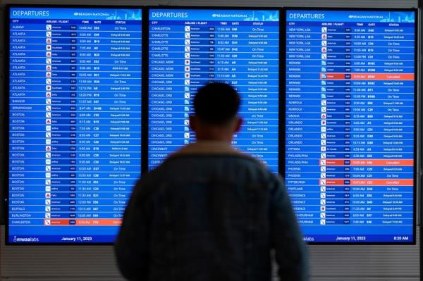 A traveler looks at a flight board with delays and cancellations at Ro<em></em>nald Reagan Washington Natio<em></em>nal Airport.