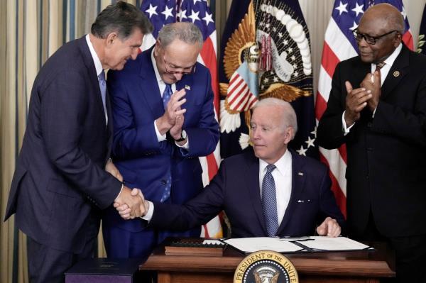 Sen. Joe Manchin shakes President Biden's hand after signing the Inflation Reduction Act last August as Senate Majority Leader Chuck Schumer looks on.  