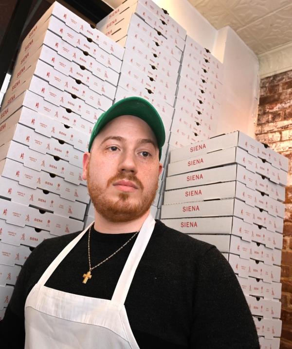Siena Pizza and Cannoli owner Fotis Liberatos standing in front of pizza boxes