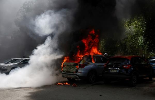 A car burns as demo<em></em>nstrators clash with police.