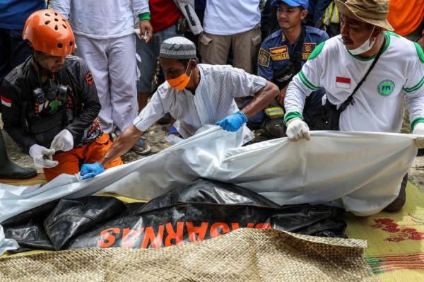 A picture of rescuers preparing the dead body of a 7-year-old girl who was killed in the earthquake.