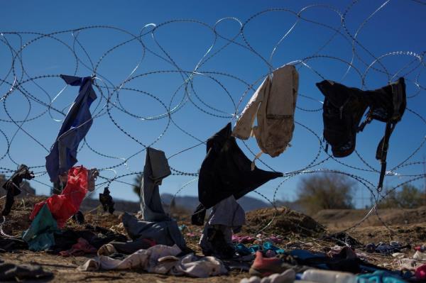 Clothes left behind by migrants seeking asylum in the U.S. hang on the razor wire of the border fence at the Rio Bravo.