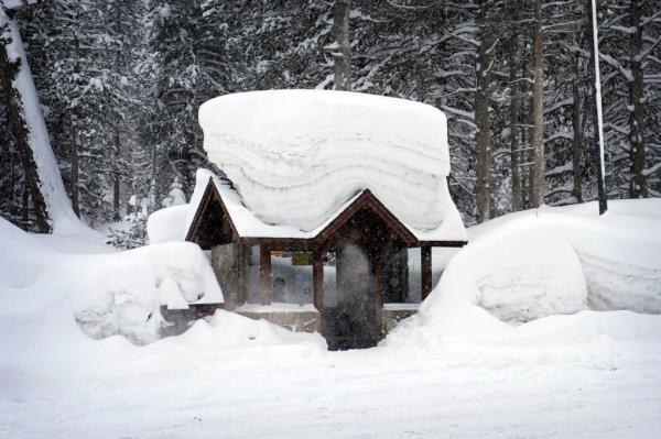 A person sits in a snow-covered bus stop Friday, Feb. 24, 2023, in Olympic Valley, Calif. California and other parts of the West are facing heavy snow and rain from the latest winter storm to pound the United States. 
