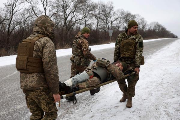 Medics of Ukrainian Army evacuate a wounded soldier on a road not far of Soleda, Ukraine.