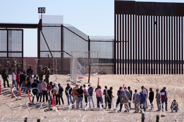 Migrants line up to be processed at the US border