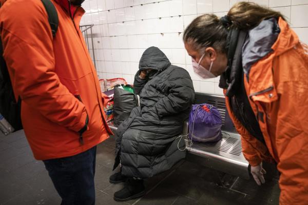 Homeless Outreach perso<em></em>nnel reach out to a person sleeping on a bench in the Manhattan subway system, Feb. 21, 2022, in New York.