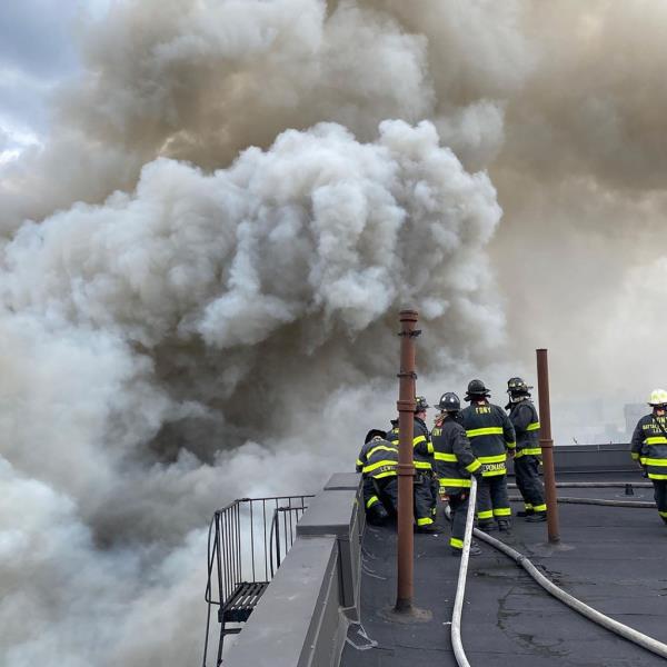 Smoke billows from the building as firefighters respond to the scene.