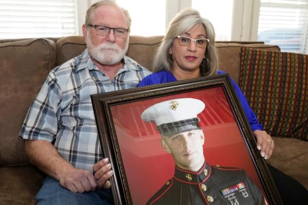 Joey and Paula Reed pose for a photo with a portrait of their son, Marine veteran and Russian priso<em></em>ner Trevor Reed, at their home in Fort Worth, Texas, Feb. 15, 2022. 
