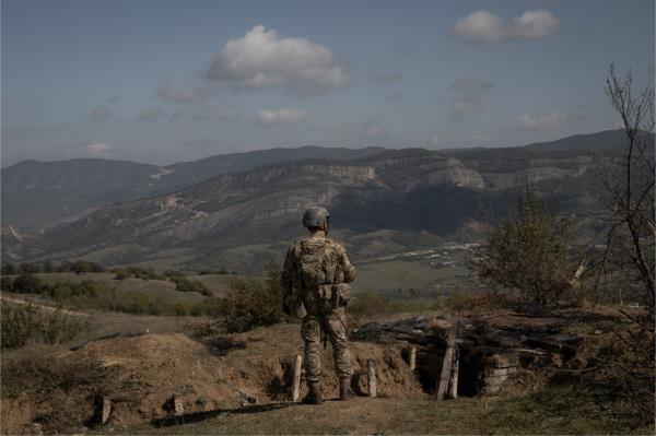 An Azerbaijani soldier in front of a burned stretch of trench at a retaken Armenian outpost.