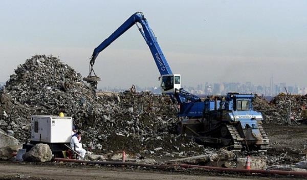 Manhattan can be seen in the background as a crane moves World Trade Center debris at the Fresh Kills Landfill 14 January, 2002. Crews at ground zero have removed 951,272 tons of debris and steel as of 03 January, according to city officials. That is roughly three fourths of the 1.2 million tons that covered the area at the outset, according to estimates by the Federal Emergency Management Agency. AFP PHOTO Don EMMERT (Photo by DON EMMERT / AFP) (Photo by DON EMMERT/AFP via Getty Images)