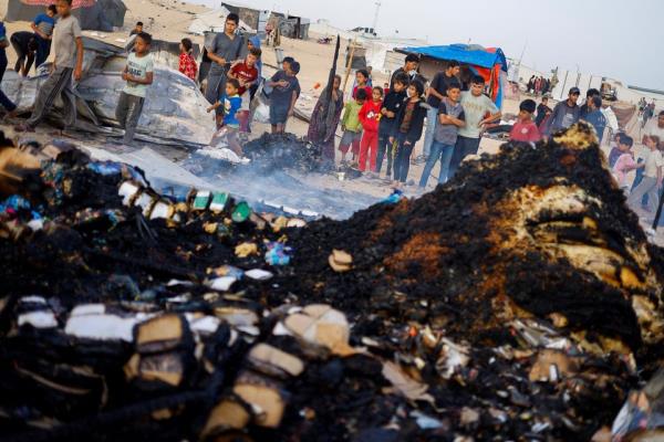 Palestinian children look at the damage while searching for food among burnt debris at the site of an Israeli strike on an area designated for displaced people, in Rafah in the southern Gaza Strip. Photo: Reuters