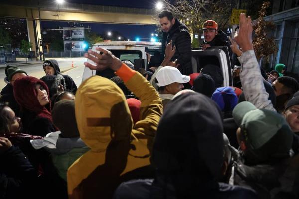 Peter Les, center background, helps distribute do<em></em>nated clothing better suited for colder weather to migrants outside the 1st District police station on Oct. 30, 2023.