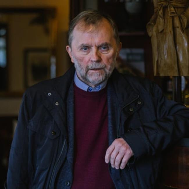 A grey-bearded man in an anorak looks squarely at the camera 