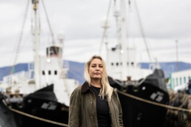 A middle-aged woman in a port looks at the camera 