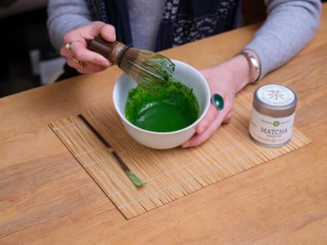 A woman stirs a bowl co<em></em>ntaining a green mixture.