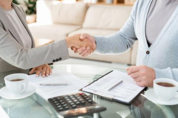 Handshake of young elegant businesswoman and her mature colleague or partner in casualwear after signing docu<em></em>ments