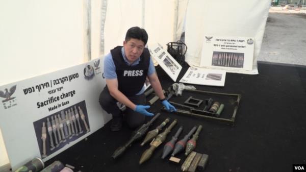 At a facility in Tzrifin, Israel, Dec. 28, 2023, VOA Korean Service reporter Jiha Ham points to weapons the Israel Defense Forces say were captured from Hamas, including North Korean-made rocket propelled grenades. (Sanghoon Lee/VOA Korean)