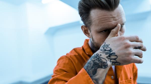Tattooed priso<em></em>ner covering face