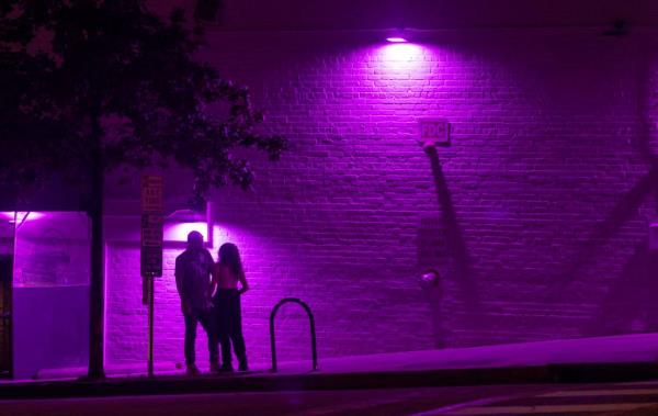 A couple talks beneath the purple glow of lights along Jo<em></em>nes Street near Halcyon Bar + Lounge on Friday July 21, 2023 in Raleigh, N.C.
