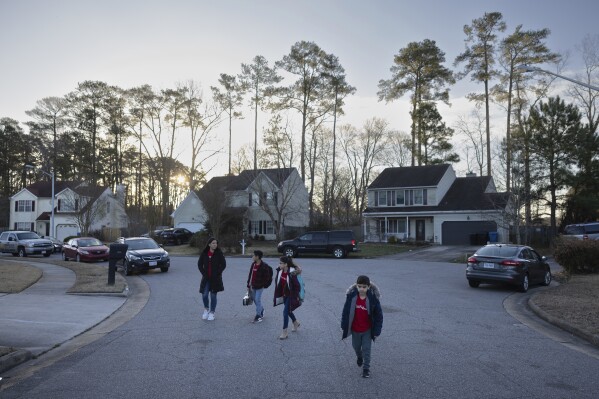 Liz Hurtado, left, walks her children to the bus stop, Tuesday, Feb. 6, 2024, in Virginia Beach, Va.  (AP Photo/Tom Brenner)