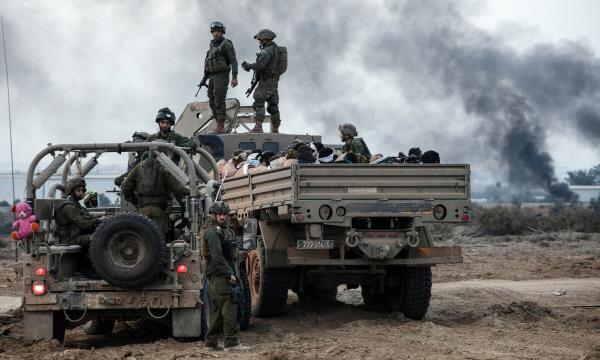  Palestinian detainees sit in a truck as Israeli soldiers guard around, in the Gaza Strip on Dec 8, 2023. — Reuters 