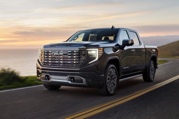 2024 gmc sierra denali ultimate 1500 crew cab short box in titanium rush me<em></em>tallic with 7 spoke ultra bright machined wheels 34 driver side front view in motion next to water