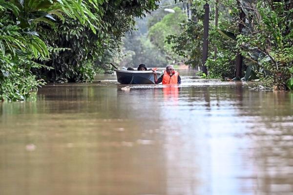 No joyride: Residents going by boat to check on their homes after they were forced to flee following rising floodwaters at Kampung Bukit Tok Bat in Kuala Berang, Terengganu. — Bernama