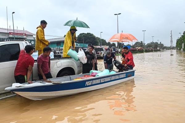 Doing the needful: Volunteers bringing essential goods by boat to flood victims in Kuala Berang. — Bernama