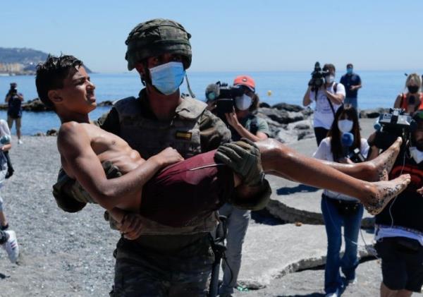 From file: A young boy is carried by a soldier in the Spanish exclave of Ceuta in May 2021 after swimming round the pier and on to Spanish territory | Photo: Reuters