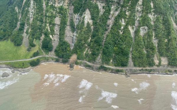 Workers in high vis clothing stand at the edge of a large hole in SH5.