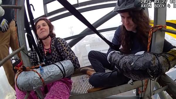 视频美国：两名活动人士被拴在起重机上，抗议拟议中的警察校园