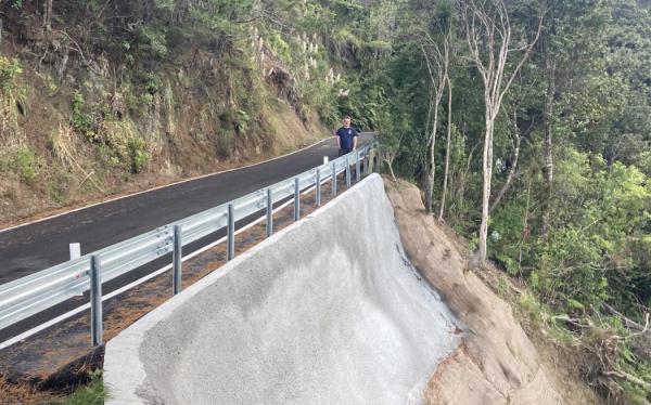 Toby Hyman next to slip repairs on Lone Kauri Road, one year after Cyclone Gabrielle.