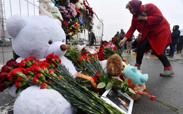 A woman lays flowers at a makeshift memorial in front of the Crocus City Hall, a day after a gun attack in Krasnogorsk, outside Moscow, on March 23, 2024. Camouflaged assailants opened fire at the packed Crocus City Hall in Moscow's northern suburb of Krasnogorsk on March 22, 2024, evening ahead of a co<em></em>ncert by Soviet-era rock band Piknik in the deadliest attack in Russia for at least a decade. Russia on March 23, 2024, said it had arrested 11 people -- including four gunmen -- over the attack on a Moscow co<em></em>ncert hall claimed by Islamic State, as the death toll rose to over 100 people. (Photo by Olga MALTSEVA / AFP)