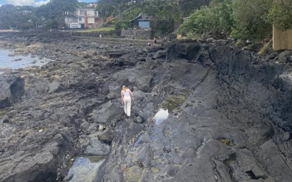 A woman negotiates rocks after the owners of a North Shore property blocked access to walkers on a popular beach path.