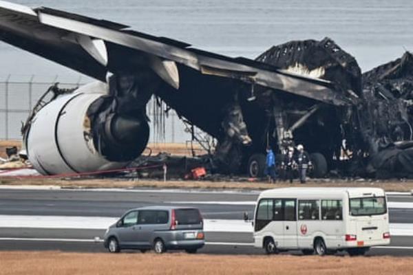 Officials examine the burnt wreckage of a Japan Airlines (JAL) passenger plane on the tarmac at Tokyo Internatio<em></em>nal Airport at Haneda.