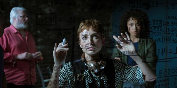 Mavournee Hazel writing on a clear board with William McInness and Olivia Swann behind her in NCIS Sydney