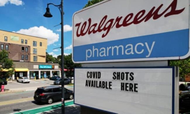 The red-on-white Walgreens logo on an outdoor sign, with letters spelling out “COVID shots available here.”