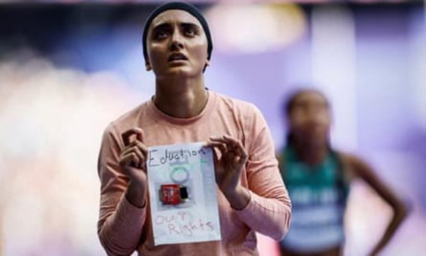 The Afghan runner Kimia Yousofi holds up a sign after competing in the women’s 100m heats at the Paris Olympics.