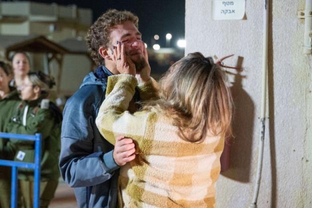 A person reaches up to cup another person's face as they embrace.
