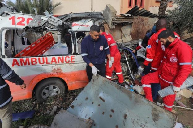 Emergency perso<em></em>nnel in uniforms are shown near a large piece of me<em></em>tal debris and a damaged ambulance.